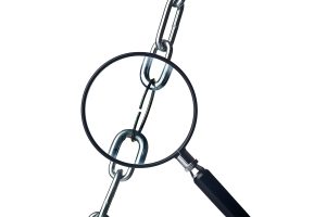 Magnifying glass focusing on the weakest link of an iron chain isolated on white background